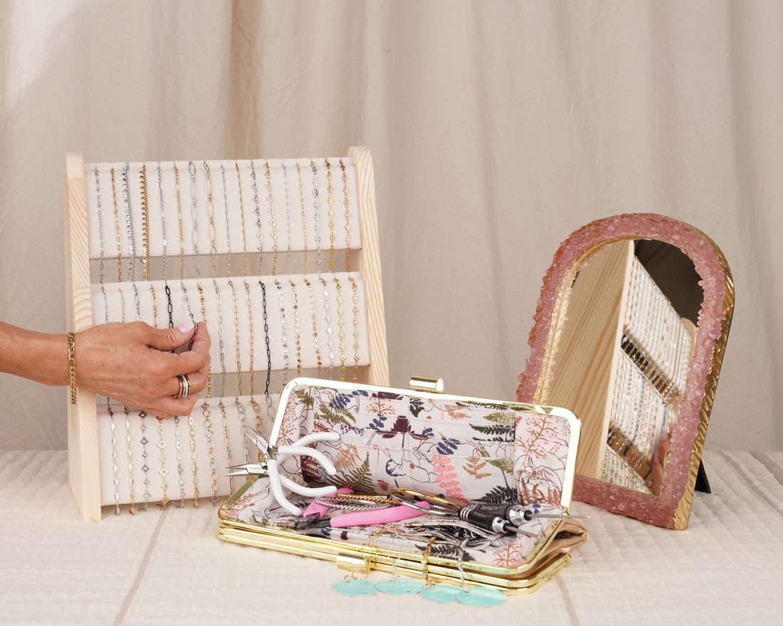 PermaLinx permanent jewelry kit with a chain display rack, tools in a floral clutch, and a mirror